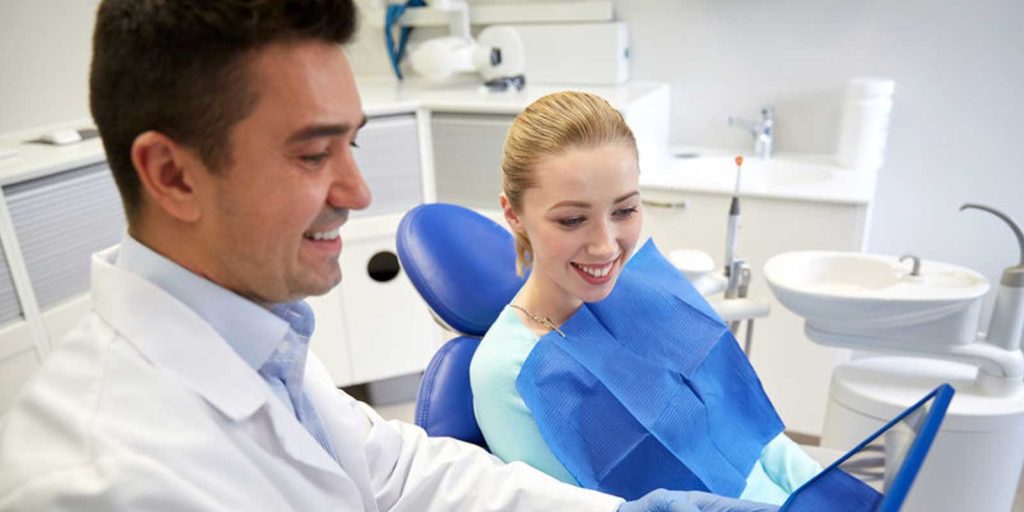 Dentist educating one of his patients by showing her his website where he used content marketing to create an article on how to properly brush your teeth