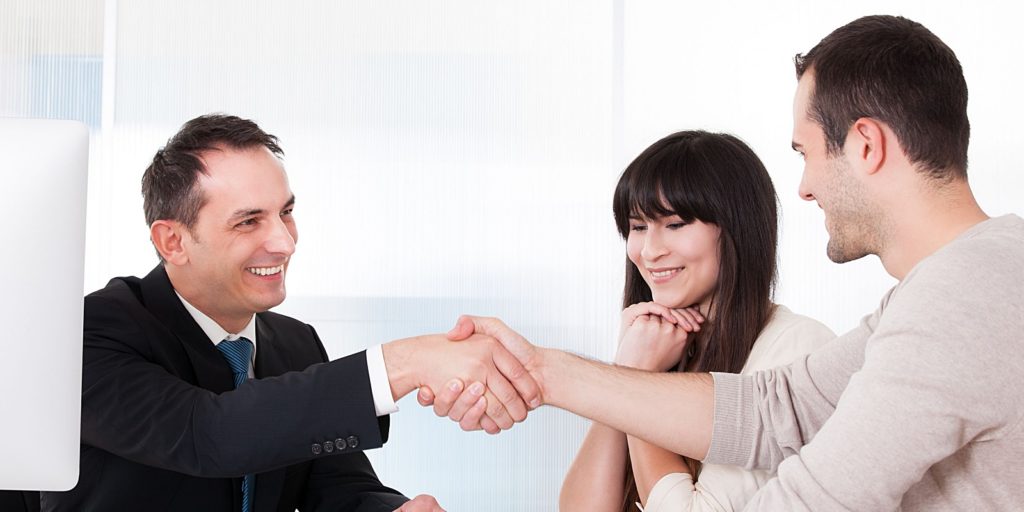 an insurance agent shaking hands with a couple who found his agency through a good insurance marketing campaign that has been running for several months