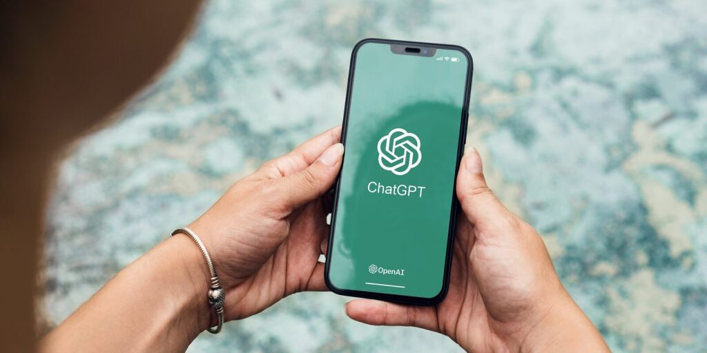 girl in the park holding a smartphone with ChatGPT artificial intelligence chatbot app on the screen