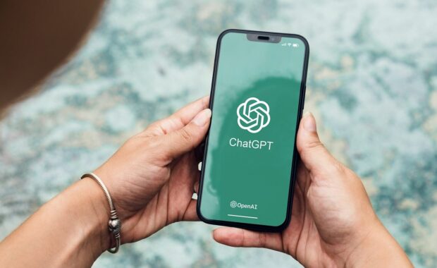 girl in the park holding a smartphone with ChatGPT artificial intelligence chatbot app on the screen