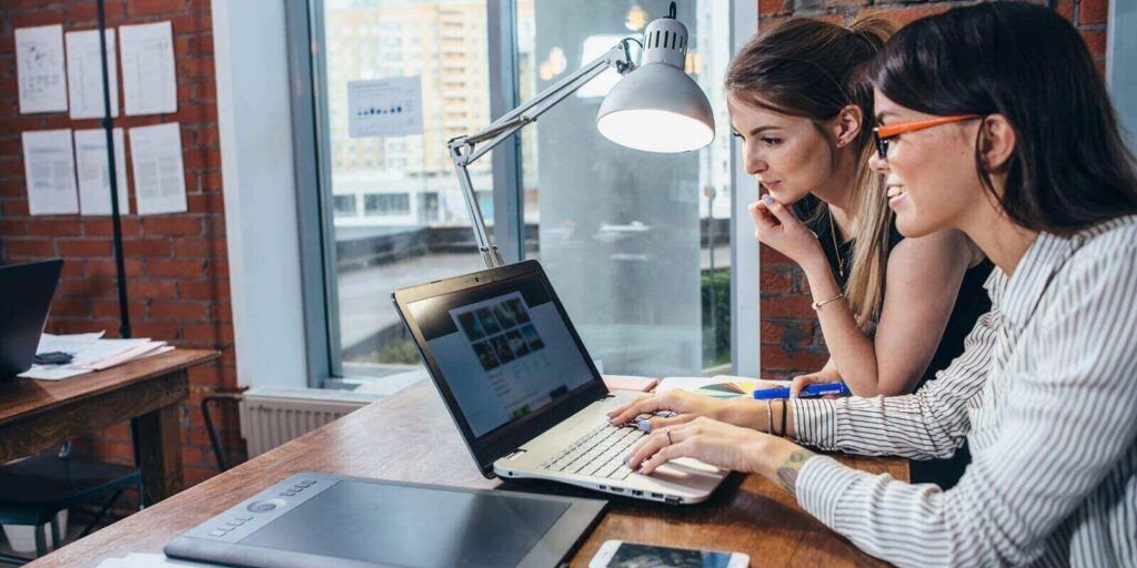 women working on new website design choosing pictures using the laptop surfing the internet